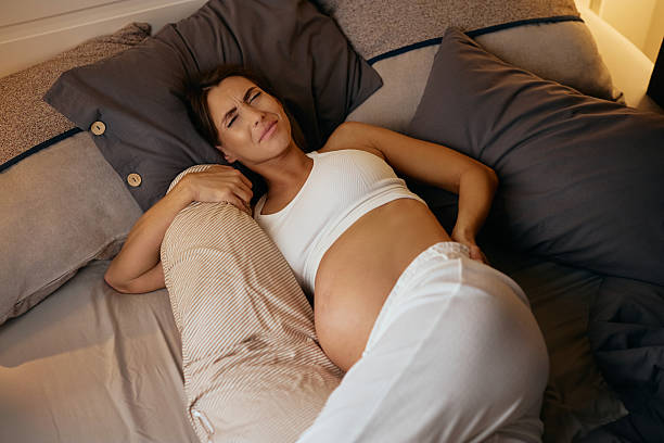 istock Young pregnant woman feeling back pain while lying down in bed. 2245018921