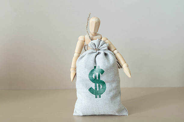istock Man pulling on a rope big bag of money, grey wall on background 2245021867