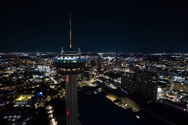 Drone shot of illuminated residential and commercial buildings in San Antonio, Texas at night.
