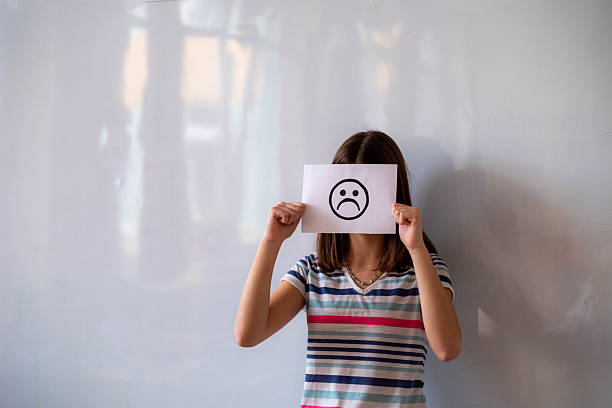 istock Teenager hiding face with sad emoticon drawing 2245032088