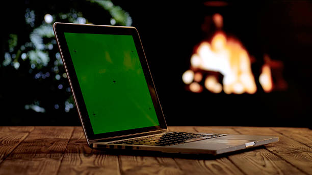 istock Laptop with a green screen chroma key screen against a cozy fireplace and Christmas tree. 2245034972