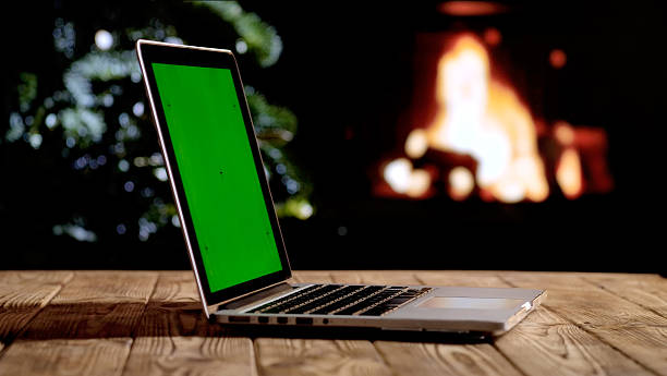 istock Laptop with a green screen chroma key screen against a cozy fireplace and Christmas tree. 2245036011