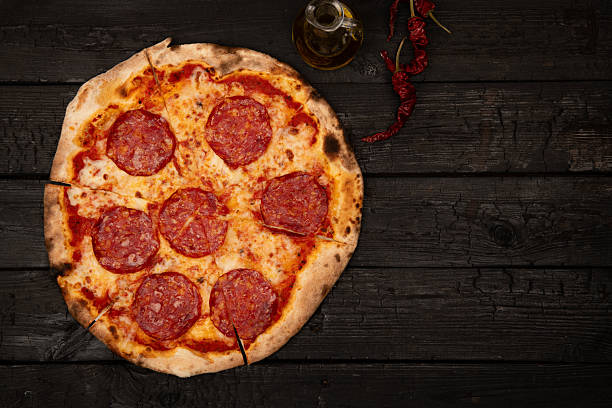 istock Whole pepperoni pizza on dark wooden table 2245043414