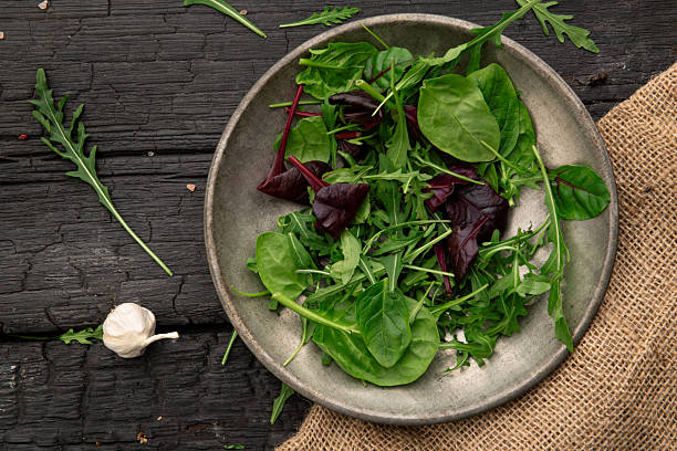 istock Fresh green salad leaves in bowl on dark table 2245043442