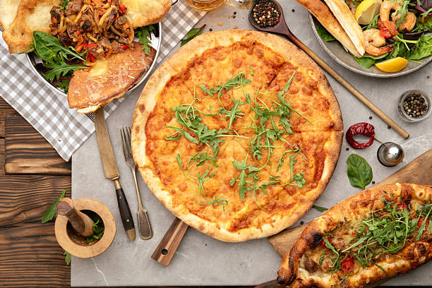 istock Pizza with herbs, olives and snacks on rustic wooden table 2245043590