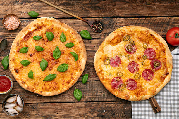 istock Two pizzas with different toppings on wooden table 2245044211