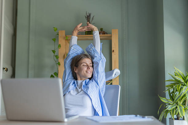 istock Happy woman stretching in a bright, inviting workspace. 2245047423
