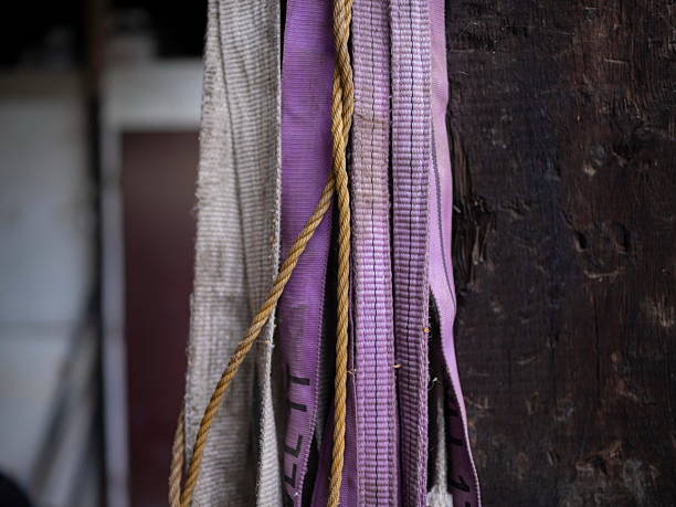 Purple and beige woven straps hanging against dark weathered wood surface in selective focus