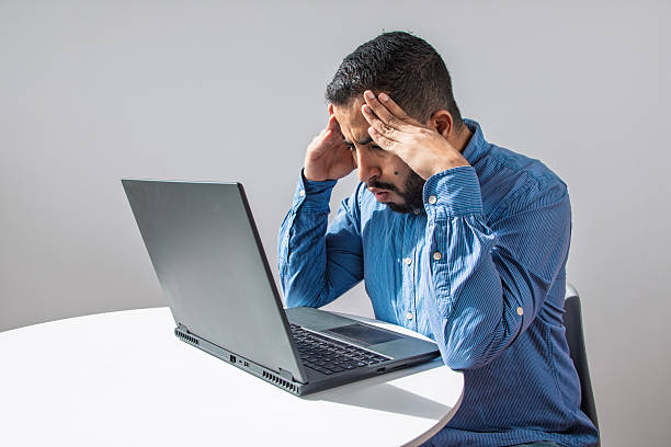 istock Stressed Man with Headache Working on Laptop 2245050014