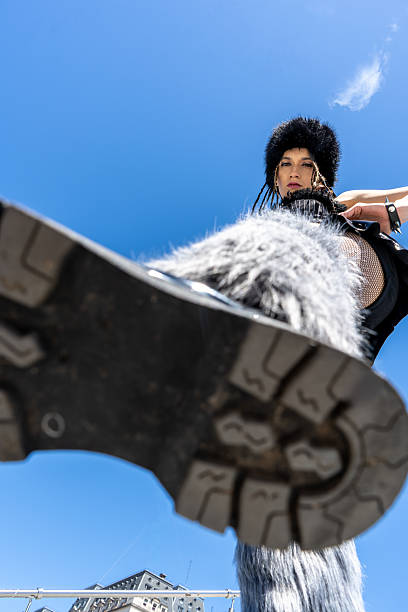 Woman in fur hat and boot stepping towards the camera from a low angle, showing power and confidence