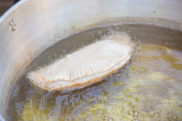 one empanada frying in a large pot with hot oil