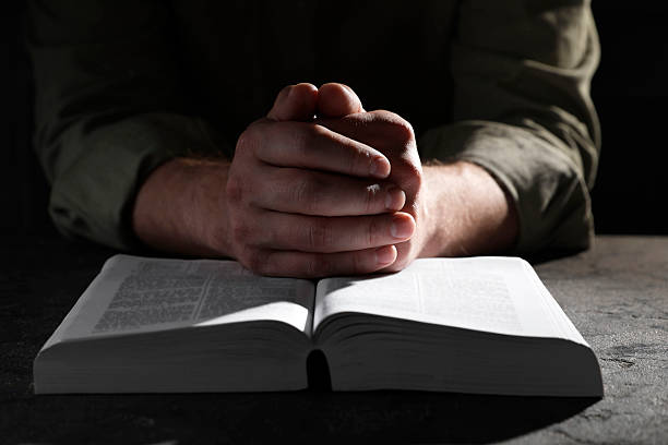 istock Religion. Christian man praying over Bible at table, closeup 2245059906