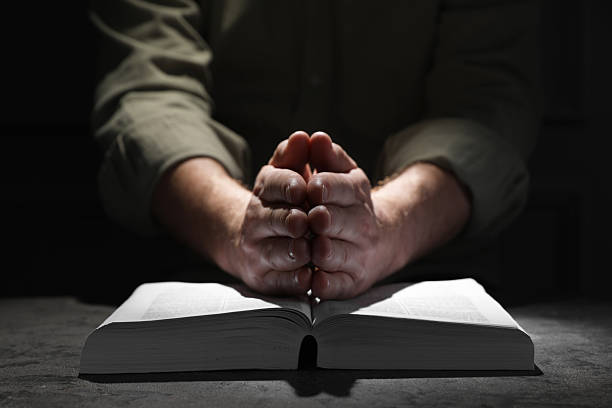 istock Religion. Christian man praying over Bible at table, closeup 2245059911