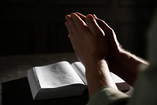 istock Religion. Christian man praying over Bible at table, closeup. Space for text 2245059914