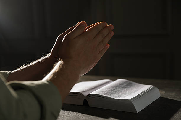 istock Religion. Christian man praying over Bible at table, closeup 2245059928