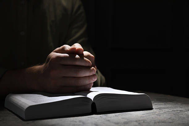 istock Religion. Christian man praying over Bible at table, closeup. Space for text 2245059932