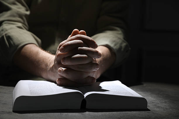 istock Religion. Christian man praying over Bible at table, closeup 2245059936