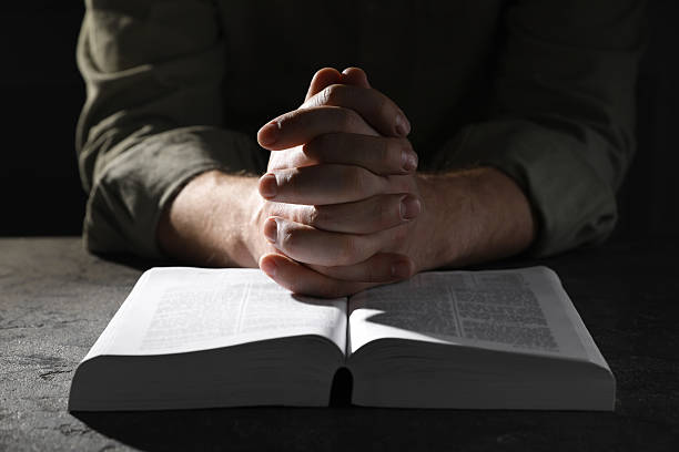 istock Religion. Christian man praying over Bible at table, closeup 2245059940