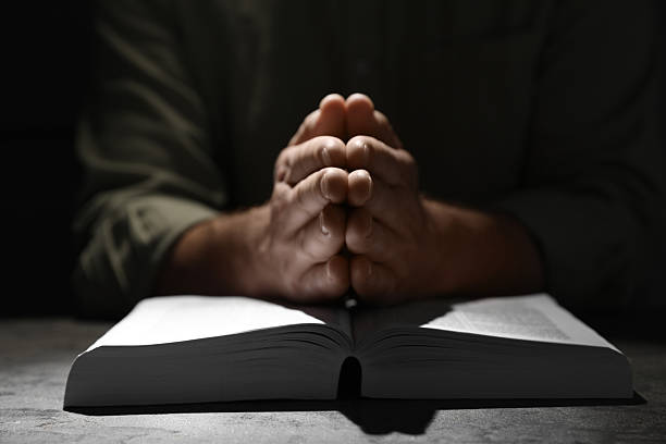 istock Religion. Christian man praying over Bible at table, closeup 2245060462