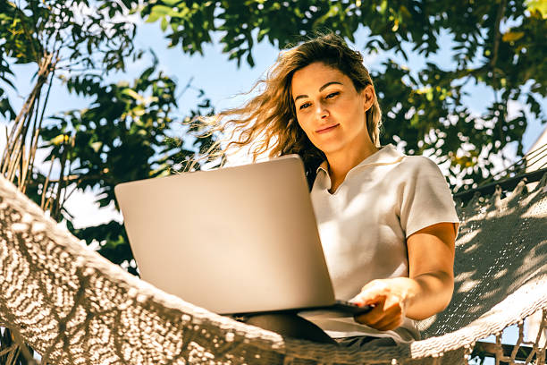 istock Woman working outdoors on laptop while sitting in hammock under bright natural daylight 2245060587
