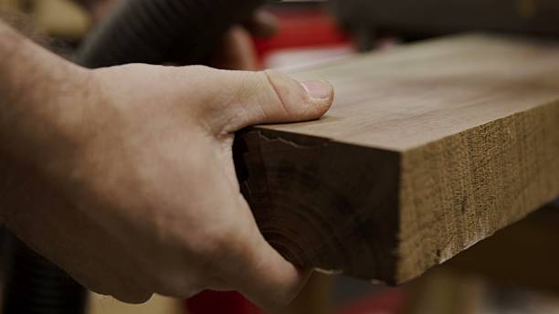 istock Carpenter's hand firmly holds a solid wood board, ready for crafting 2245061725