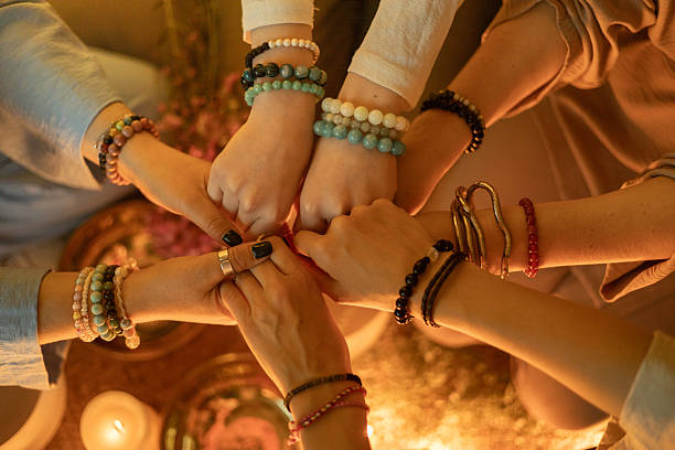 istock Group unity ritual with hands joined in circle wearing crystal bead bracelets in warm light 2245062410