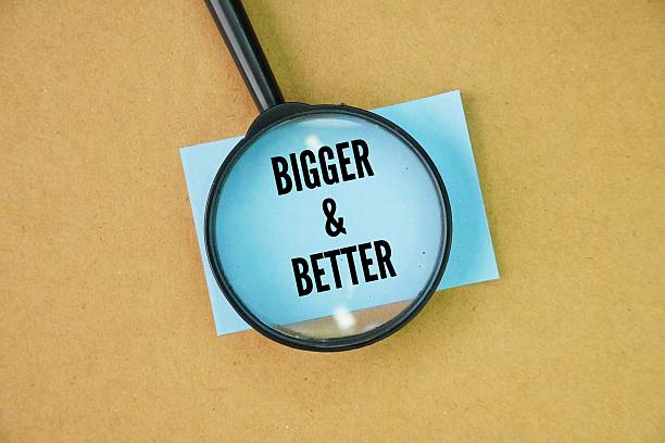 istock Magnifying glass and paper with the words bigger and better. 2245062464