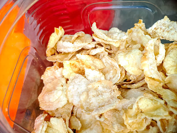 istock Golden, crispy chip snacks sit inside a vibrant container with bright red and orange hues. 2245064175