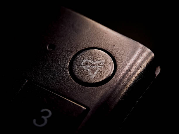 Abstract capture shows a textured surface with an inset button and geometric mark lit dramatically.