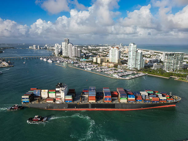 istock Miami, Florida, USA - December 17, 2024: Cargo ship with container and tugboat in Miami. Freight container loaded on cargo vessel in Miami. Aerial view cargo ship entering harbor. Container ship 2245068994