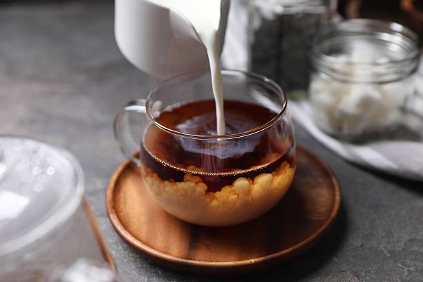istock Pouring milk into cup of tea on grey table, closeup 2245071207