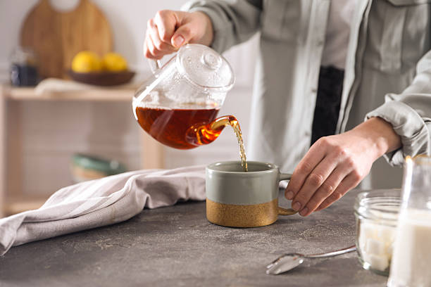 istock Woman pouring hot tea into cup at grey table, closeup 2245071219