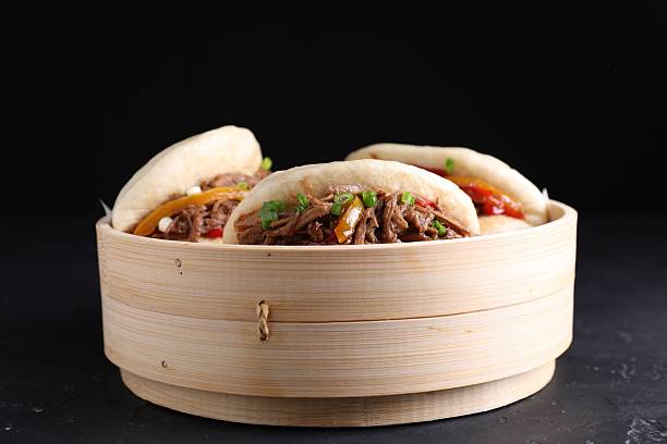 istock Delicious gua bao in bamboo steamer on black table 2245072200