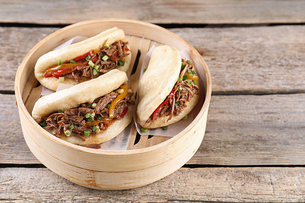 istock Delicious gua bao in bamboo steamer on wooden table. Space for text 2245073452
