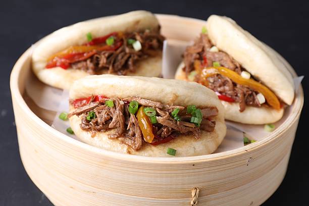 istock Delicious gua bao in bamboo steamer on black table, closeup 2245073753