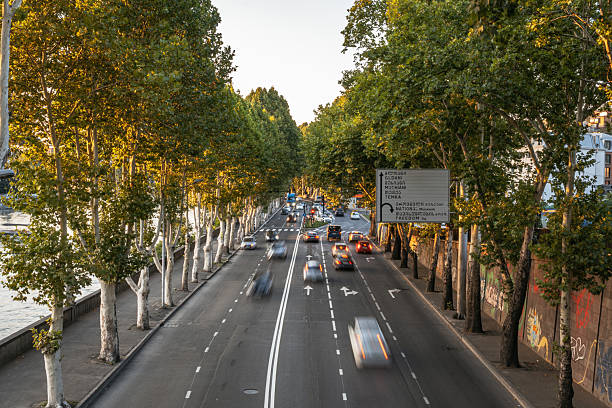 istock Motion blur traffic on a tree-lined avenue with a river at sunset 2245075252