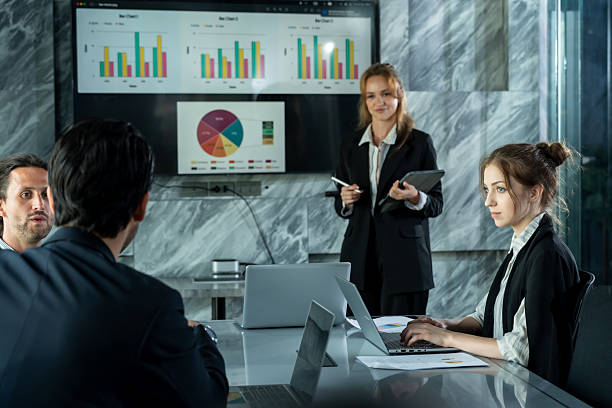 istock Multiracial business team discussing charts during meeting inside modern office, caucasian female executive presenting graph while coworkers listening and reviewing financial documents together 2245077726