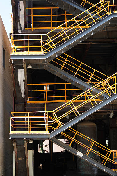 An industrial multi - level steel staircase with yellow safety rails, showing industrial construction and safety features.