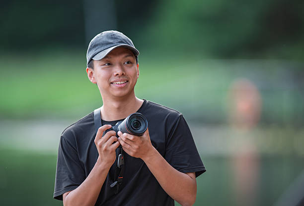 istock Young Asian Chinese Photographer Smiling Outdoors While Holding a Professional Camera 2245079342