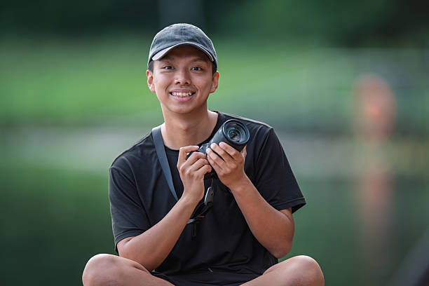 istock Young Asian Chinese Photographer Smiling Outdoors While Holding a Professional Camera 2245079362