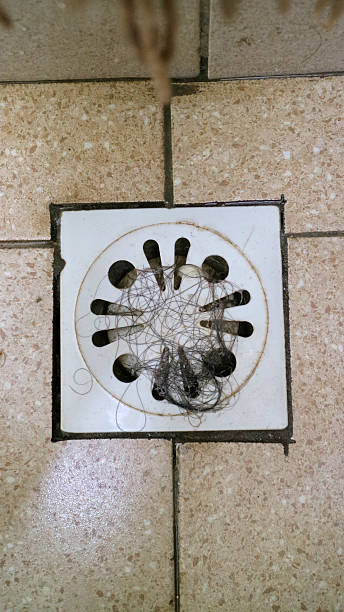 istock Hair clog blocking white bathroom floor drain cover 2245079572