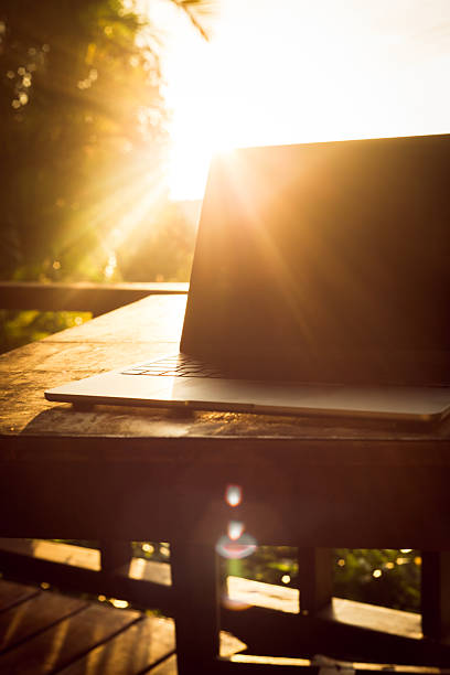 istock Laptop with backlight on wooden table on terrace in tropical forest at sunset, remote work digital nomad 2245084896
