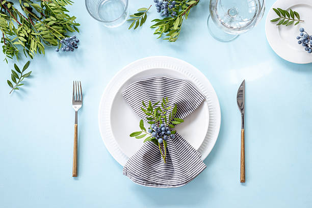 istock Festive table setting with empty plate and glasses, cutlery and napkin - green leaves decorated, flat lay. Top view 2245085708