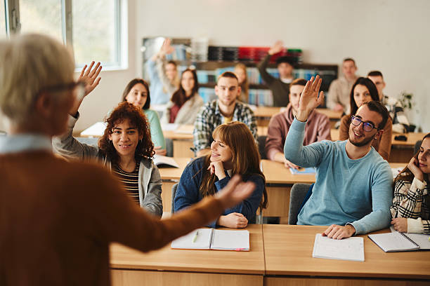 istock Happy students raising hands on a class in the classroom. 2245086153