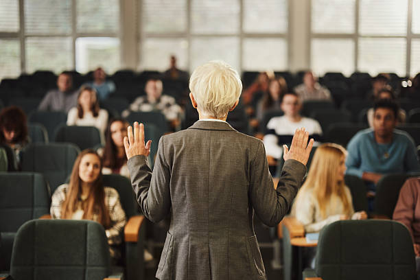istock Back view of a female professor teaching her students at lecture hall. 2245087126