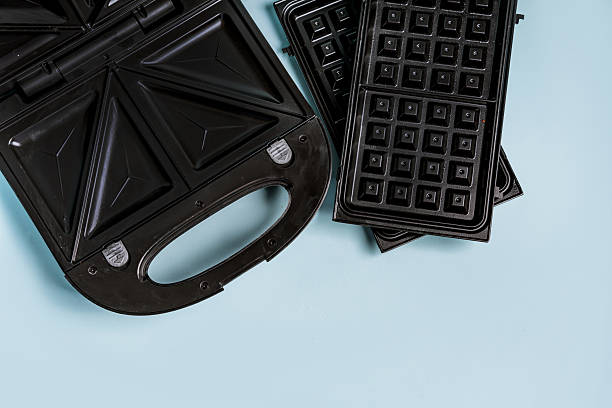 istock Electric waffle iron with nozzles for sandwiches and waffles on a blue background 2245087607