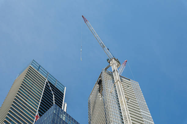High rise city building under construction with crane attached on a sunny day.