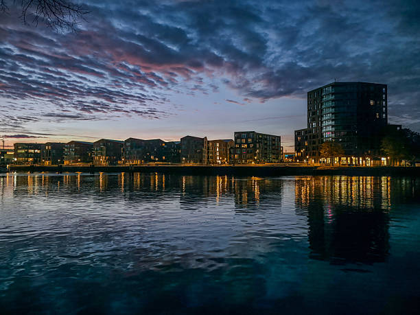 istock Buildings are reflected in the illuminated water at dawn with a dramatic sky, sunrise, River Hunte at the harbor promenade of 26122 Oldenburg, Germany 2245090425