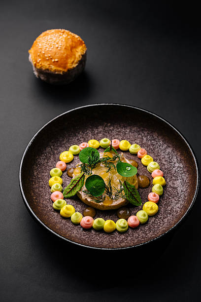 istock Unique circular dish with colorful garnishes and a bread roll in a dark setting 2245090500