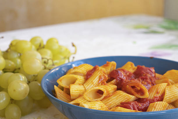 Delicious penne pasta in rich tomato sauce garnished with fresh basil leaves, served on white plate